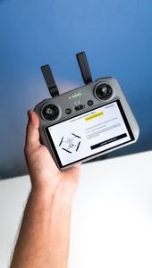 Close-up of a person holding a drone controller with a screen displaying drone setup instructions.