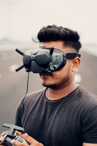 Young man using drone goggles and controller for immersive outdoor experience.